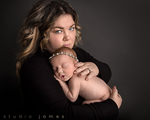 new mother holding her baby girl at calgary newborn photography studio