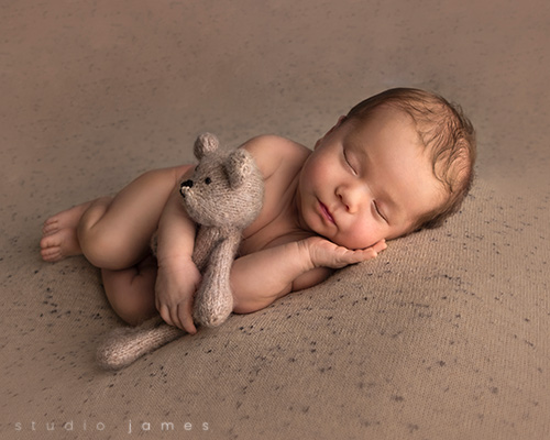 Calgary newborn baby boy holding a teddy bear in newborn photography session