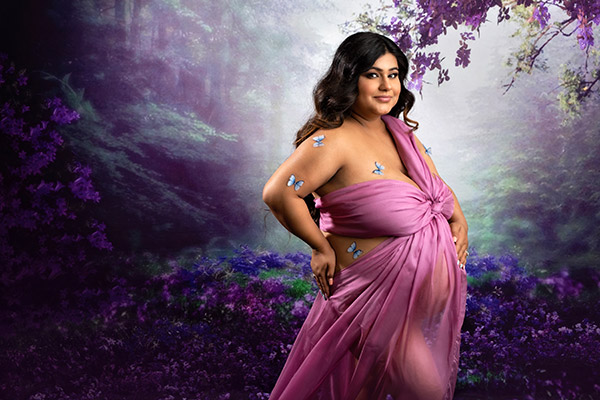 picture of third trimester pregnant woman in maternity photoshoot in Calgary. Wearing a pink dress with butterflies